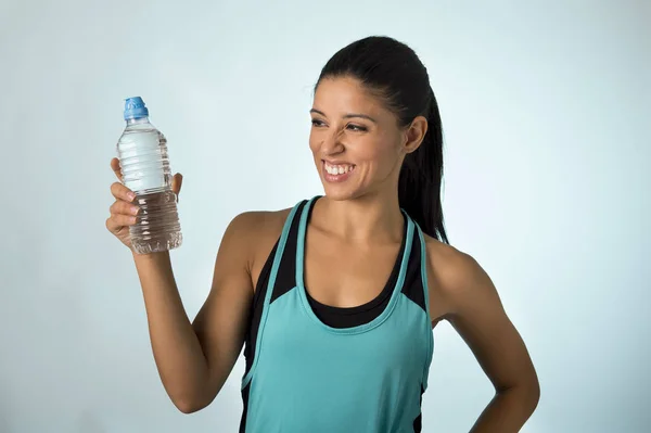 Felice e attraente donna di sport latino in abiti fitness in possesso di bottiglia di acqua potabile sorridente fresco e allegro — Foto Stock