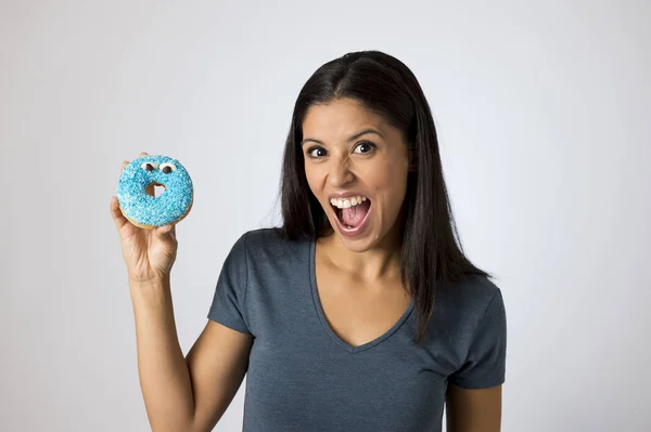 Feliz atractiva latina sonriente excitada sosteniendo donut de azúcar aislado sobre fondo claro en el abuso del azúcar —  Fotos de Stock