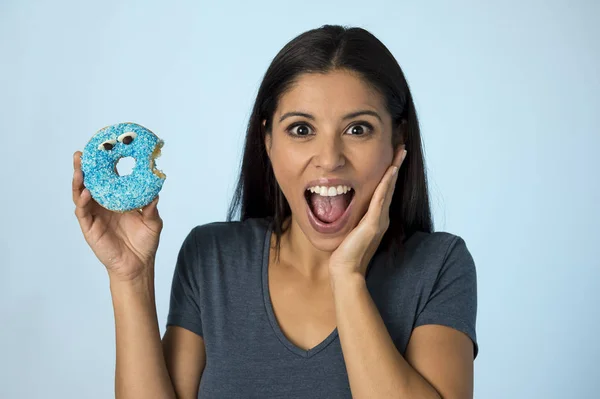 Счастливая привлекательная латиноамериканка улыбается взволнованный держа сахар пончик изолирован на четком фоне в злоупотреблении сахаром — стоковое фото