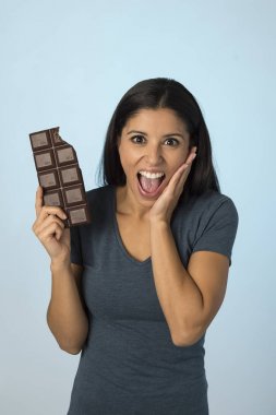 Mavi top gülümseyen içinde genç çekici ve mutlu İspanyol kadın izole arka plan çikolata yeme heyecanlı