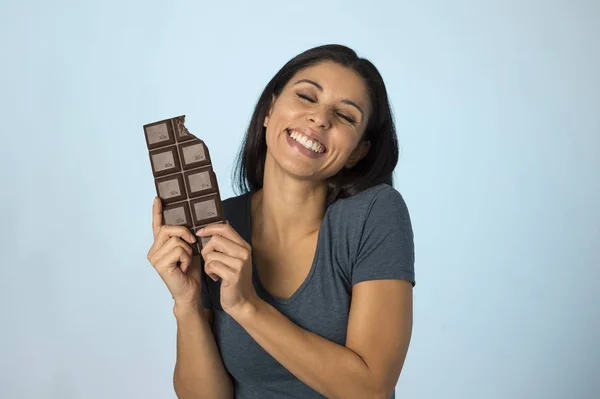 Mladá atraktivní a šťastný hispánský žena v modrý top s úsměvem nadšený, jíst čokoláda izolované pozadí — Stock fotografie