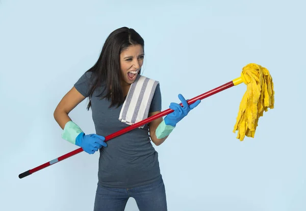 Young attractive happy Latin woman in washing gloves holding mop having fun singing and playing air guitar excited — Stock Photo, Image