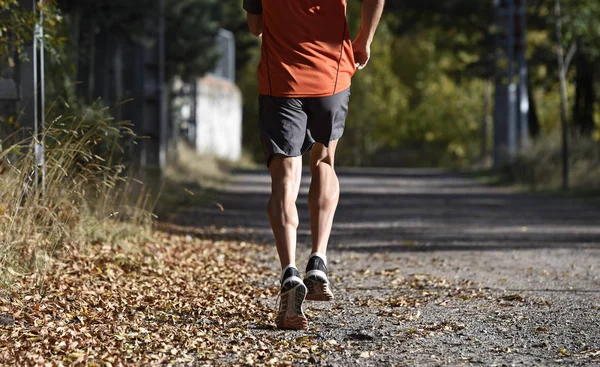 Sportler mit gerissenen athletischen und muskulösen Beinen beim Jogging-Training auf dem Land im Herbst-Hintergrund — Stockfoto
