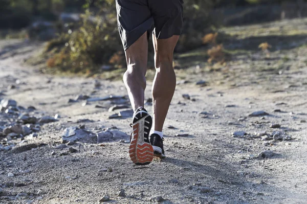 Deportista con piernas musculosas y atléticas arrancadas corriendo fuera de la carretera en el entrenamiento de jogging en el campo en el fondo de otoño — Foto de Stock