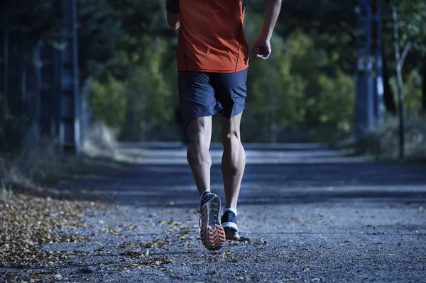 Homem do esporte com pernas atléticas e musculares rasgadas correndo fora da estrada em treino de corrida no campo no fundo Outono — Fotografia de Stock