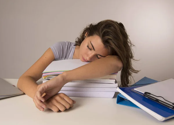 Young attractive and beautiful tired student girl leaning on school books pile sleeping tired and exhausted after studying — Stock Photo, Image