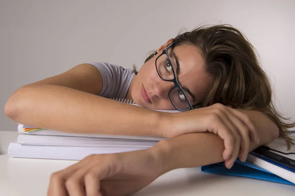 Young attractive and beautiful tired student girl leaning on school books pile sleeping tired and exhausted after studying — Stock Photo, Image