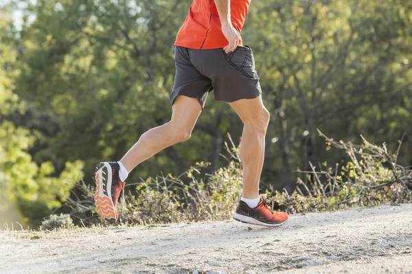 Hombre deportivo con piernas atléticas y musculosas rasgadas corriendo downhil — Foto de Stock