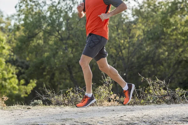 Hombre deportivo con piernas atléticas y musculosas rasgadas corriendo downhil —  Fotos de Stock