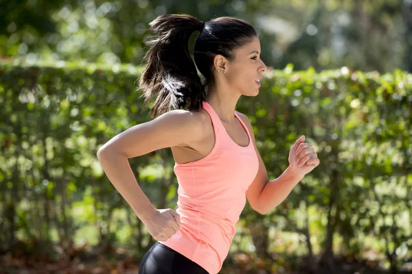 Attraktive und glückliche Läuferin in herbstlicher Sportbekleidung beim Joggen im Stadtpark — Stockfoto