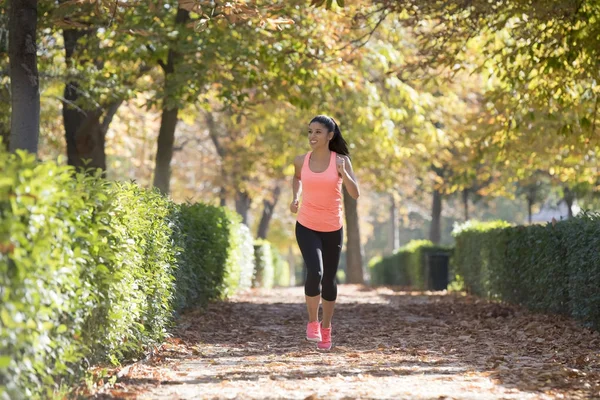 Mujer corredora atractiva y feliz en ropa deportiva de otoño corriendo un — Foto de Stock