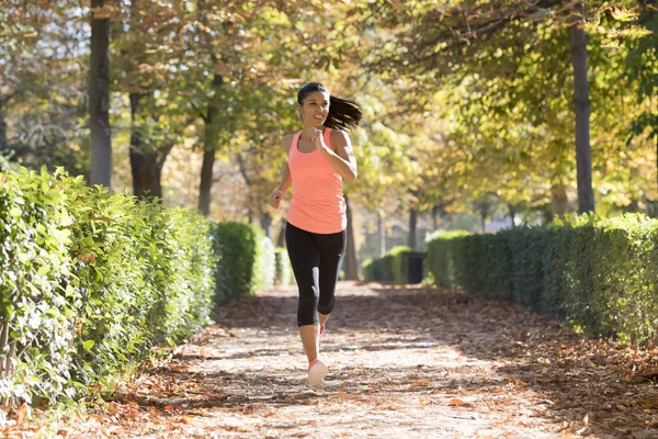 Mujer corredora atractiva y feliz en la ropa deportiva de otoño correr y entrenar en correr al aire libre entrenamiento en el parque de la ciudad — Foto de Stock