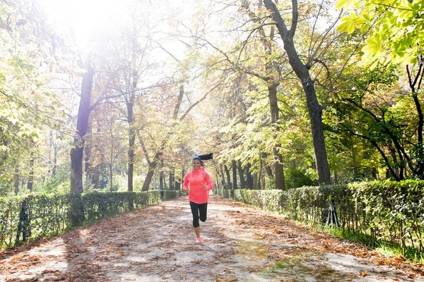 Mujer corredora atractiva y feliz en ropa deportiva de otoño corriendo un — Foto de Stock