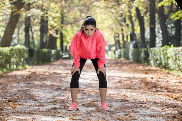 Atractiva mujer deportiva en corredor ropa deportiva respirando jadeando y tomando un descanso cansado y agotado después de correr entrenamiento en el parque de otoño — Foto de Stock