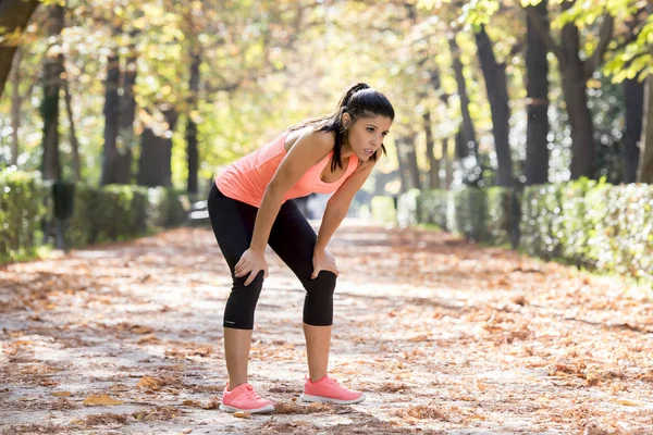 Atractiva mujer deportiva en corredor ropa deportiva respirando jadeando y tomando un descanso cansado y agotado después de correr entrenamiento en el parque de otoño —  Fotos de Stock