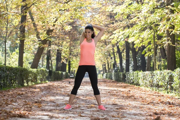 Hermosa mujer deporte hispano en ropa deportiva estiramiento cuerpo siguiente sonriente feliz haciendo ejercicios de flexibilidad — Foto de Stock