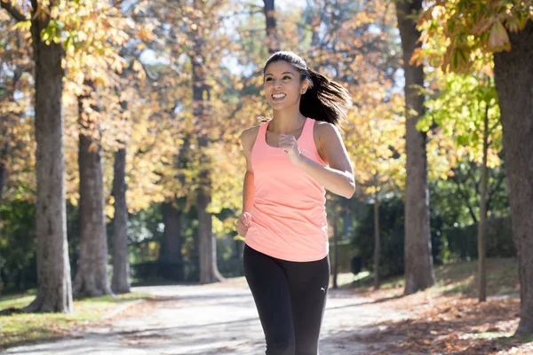 Mujer corredora atractiva y feliz en la ropa deportiva de otoño correr y entrenar en correr al aire libre entrenamiento en el parque de la ciudad — Foto de Stock