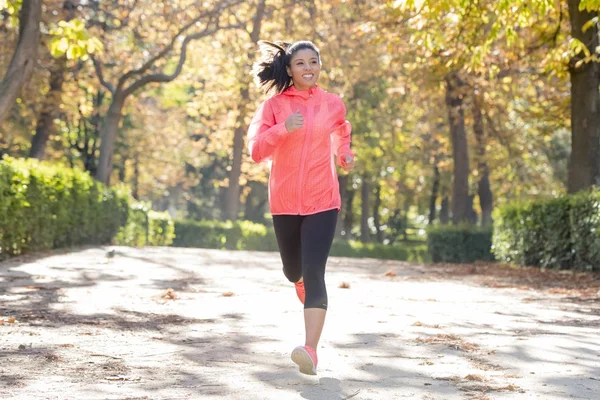 Mujer corredora atractiva y feliz en ropa deportiva de otoño corriendo un — Foto de Stock