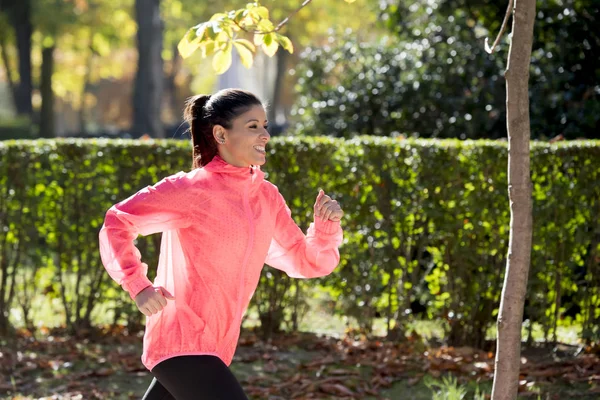 Mujer corredora atractiva y feliz en la ropa deportiva de otoño correr y entrenar en correr al aire libre entrenamiento en el parque de la ciudad — Foto de Stock