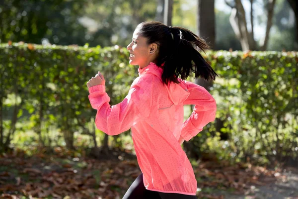 Mujer corredora atractiva y feliz en la ropa deportiva de otoño correr y entrenar en correr al aire libre entrenamiento en el parque de la ciudad — Foto de Stock