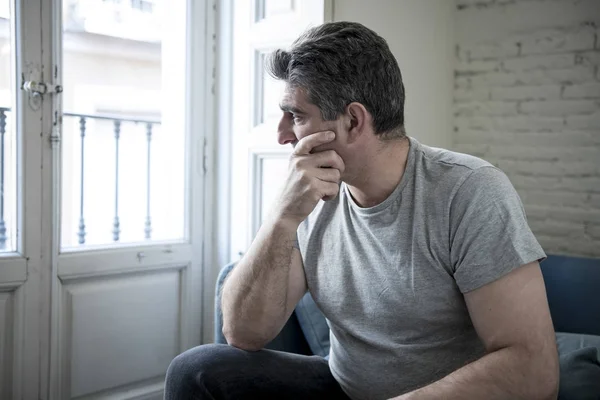 Triste e preocupado homem com cabelos grisalhos sentado em casa sofá olhando — Fotografia de Stock