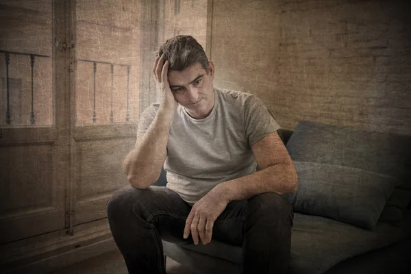 Sad and worried man with grey hair sitting at home couch looking — Stock Photo, Image