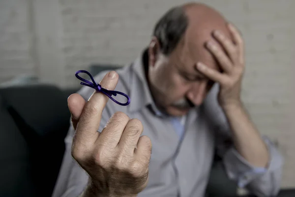 Maduro velho em seus 60 anos em casa sofá sozinho sentindo triste e preocupado sofrendo alzheimer doença segurando fita — Fotografia de Stock