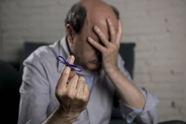 Pria tua yang matang pada usia 60-an di sofa rumah sendirian merasa sedih dan khawatir menderita penyakit alzheimer memegang pita — Stok Foto
