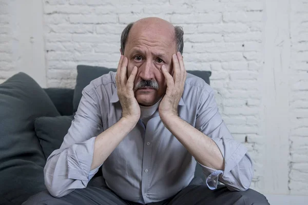 Retrato de idoso maduro sênior em seus 60 anos em casa sofá sozinho sentindo triste e preocupado sofrendo dor e depressão — Fotografia de Stock