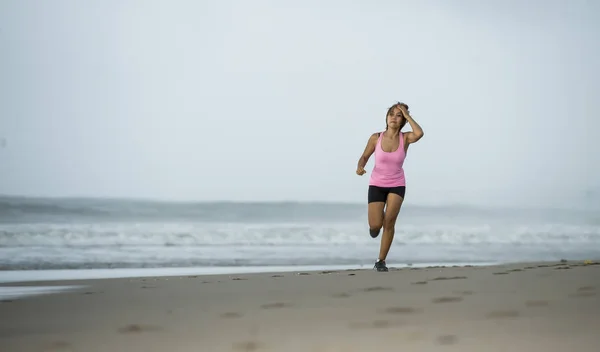 young attractive and fit Asian sport runner woman running on beach sea side smiling happy in fitness