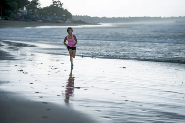 Junge attraktive und fitte asiatische Sportläuferin, die am Strand am Meer läuft und glücklich in Fitness lächelt — Stockfoto