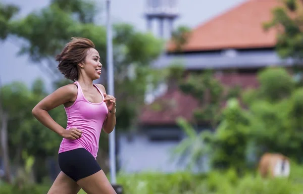 Νέοι Ασιατικές Αθλητισμός γυναίκα δρομέας τρέχει στη ζούγκλα χαμογελά ευτυχισμένη με προπόνηση στο φόντο το χορτάρι στο γυμναστήριο — Φωτογραφία Αρχείου