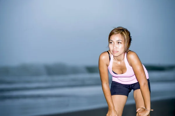 Pelari wanita Asia yang cocok sedang mendinginkan nafas setelah berlari di sisi pantai tampak lelah sementara latihan keras — Stok Foto