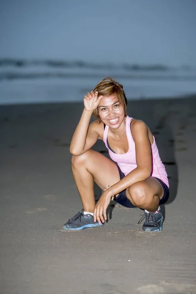 Junge attraktive und fitte asiatische Sportlerin läuft am Strand am Meer und sieht müde und glücklich lächelnd aus, während sie hart trainiert — Stockfoto