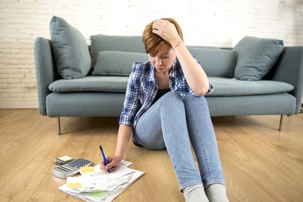 Young sad worried and desperate woman banking and accounting home monthly and credit card expenses on living room floor — Stock Photo, Image