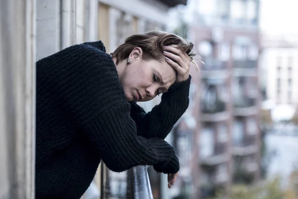 Junge schöne Frau denkt und fühlt sich traurig und leidet unter Depressionen auf dem städtischen Heimatbalkon — Stockfoto