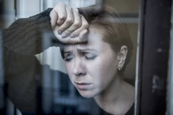 Drammatico ritratto ravvicinato di giovane bella donna che pensa e si sente triste depressione sofferenza alla finestra di casa guardando depresso — Foto Stock