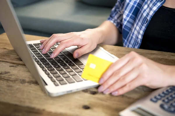 Close-up van de hand van vrouw met credit card on-line winkelen of bankieren op internet met laptopcomputer thuis in de binnenlandse financiële sector — Stockfoto