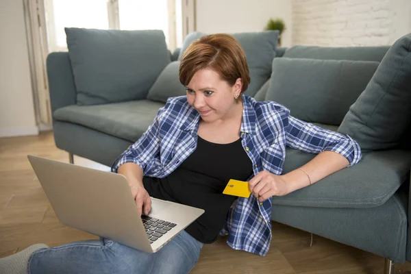 Muda menarik dan bahagia wanita di sofa rumah dengan kartu kredit dan komputer laptop belanja di baris atau rekening dalam negeri perbankan — Stok Foto