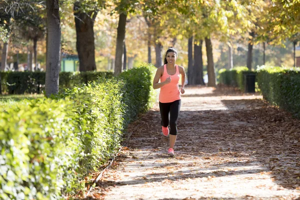 Mujer corredora atractiva y feliz en ropa deportiva de otoño corriendo un — Foto de Stock