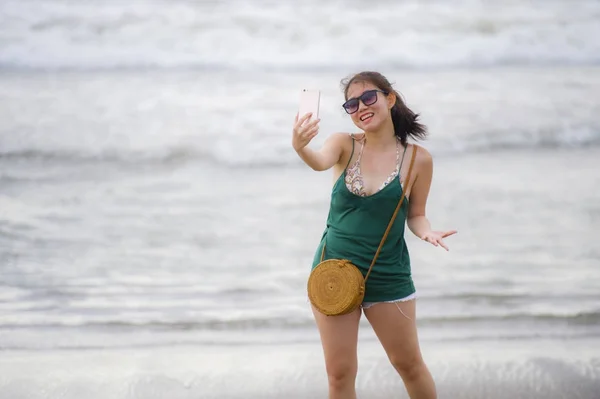 Joven bonita y dulce china asiática mujer en la playa tomando foto selfie retrato con cámara de teléfono móvil disfrutando de vacaciones feliz — Foto de Stock