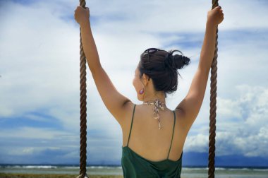 arkadan görünüşü eğleniyor salıncak ipi tutan genç güzel ve mutlu Asyalı Çinli kadın 