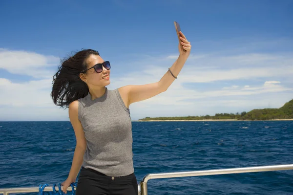 Jeune attrayant et heureux asiatique femme chinoise selfie portrait photo avec téléphone mobile sur bateau ou ferry souriant avec fond bleu mer — Photo
