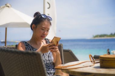 rahat Asyalı Çinli kadın Island tatil Resort sahilde oturan metin gönderme cep telefonunda internet sosyal medya kullanarak 