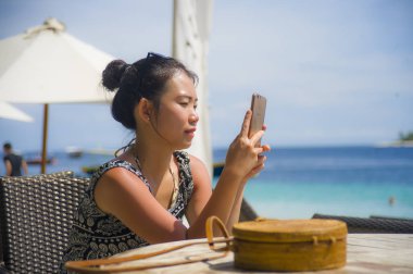 rahat Asyalı Çinli kadın Island tatil Resort sahilde oturan metin gönderme cep telefonunda internet sosyal medya kullanarak 