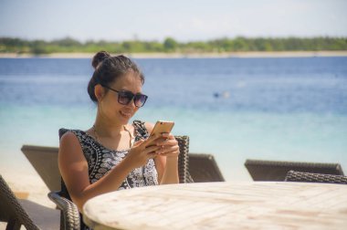 rahat Asyalı Çinli kadın Island tatil Resort sahilde oturan metin gönderme cep telefonunda internet sosyal medya kullanarak 