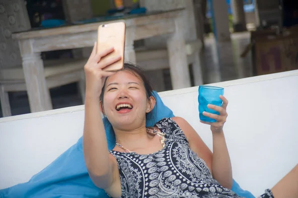 Joven dulce y bonita asiática china mujer sentado en playa vacaciones resort tomando foto selfie en el teléfono móvil feliz y emocionado — Foto de Stock