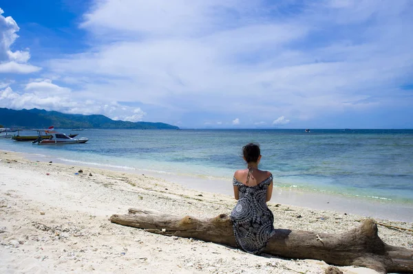 Giovane donna asiatica seduta sul tronco a spiaggia di sabbia bianca a Bali I — Foto Stock