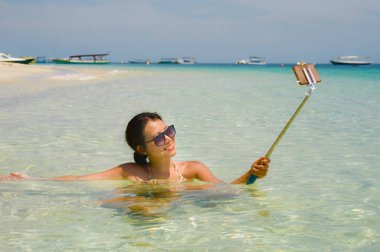 Deniz suyu selfie fotoğrafını cep telefonu kamera ile Cennet plaj üzerinde eğleniyor genç güzel ve mutlu Asyalı Çinli kadın