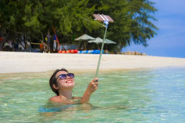 Deniz suyu selfie fotoğrafını cep telefonu kamera ile Cennet plaj üzerinde eğleniyor genç güzel ve mutlu Asyalı Çinli kadın